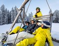 Skigebiet: Eine kurze Verschnaufpause mit der ganzen Familie auf einer Holzschaukel - Skigebiet Filzmoos